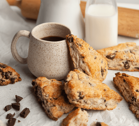 chocolate chunk scones with coffee and milk and chocolate pieces surrounding them